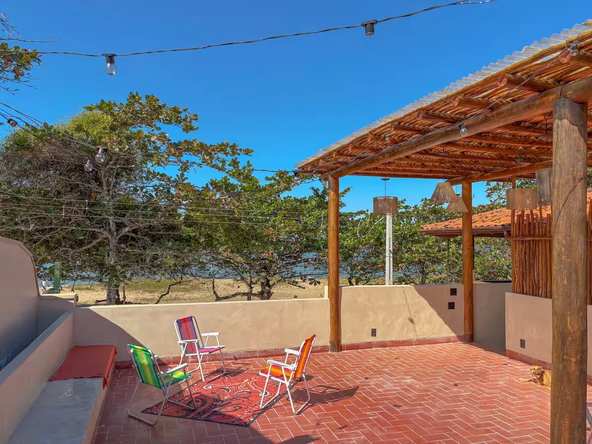 Rooftop da Casa Tohmé, com pergolado de bambu, varal de luzes, cadeiras de praia e a praia ao fundo